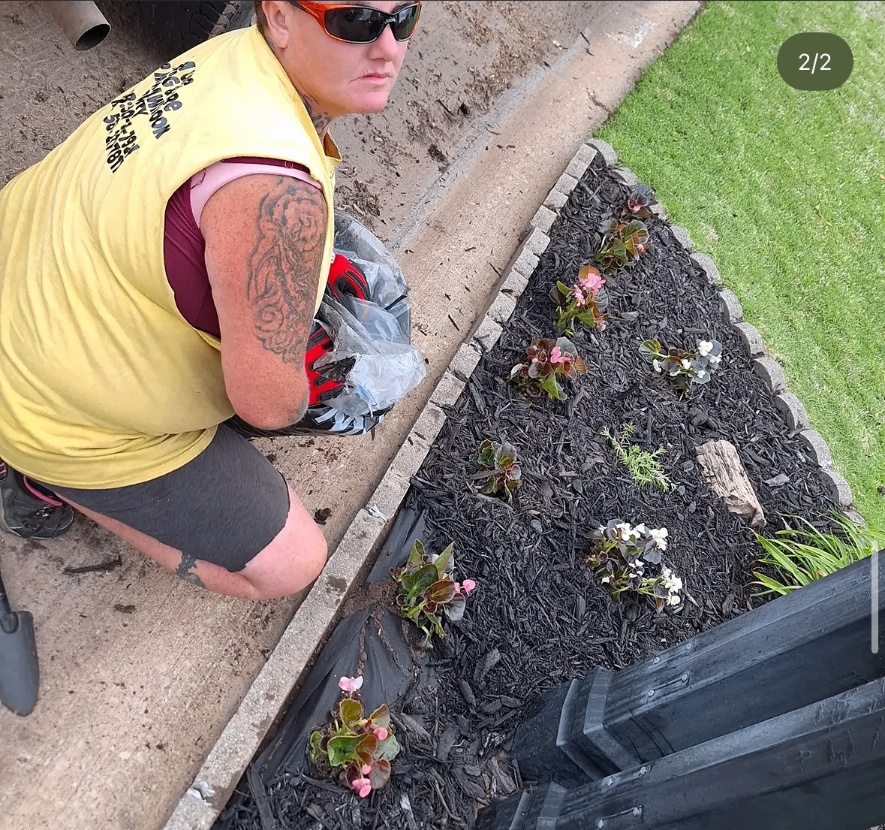 AlaCarte Mowing & More team member working in a freshly mulched flower bed